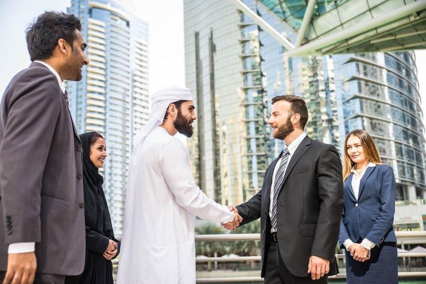 Multinárodná skupina podnikateľov na outdoorovom stretnutí v Dubaji.