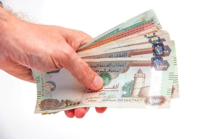 Muž držiaci bankovky Spojených arabských emirátov.
