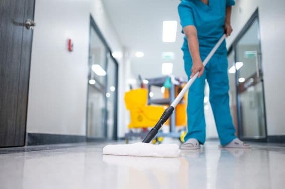 Upratovačka, ktorá vytiera podlahu haly.