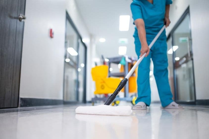 Upratovačka, ktorá vytiera podlahu haly.