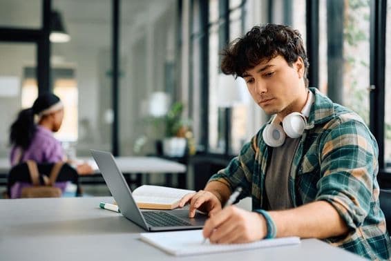 Univerzitný študent používajúci notebook pri písaní.