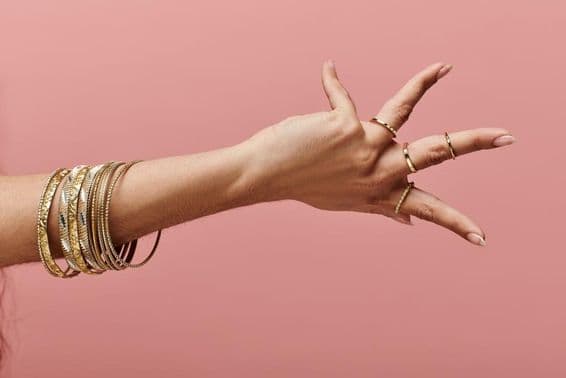 Indická žena elegantne pózuje so zlatými náramkami na zápästí.