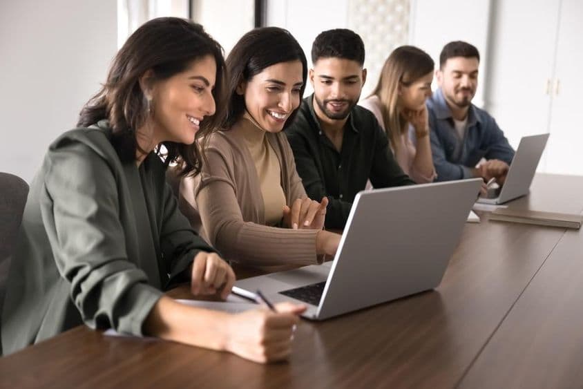 Multinárodní mladí dospelí študenti študujúci na notebookoch v vzdelávacom centre.