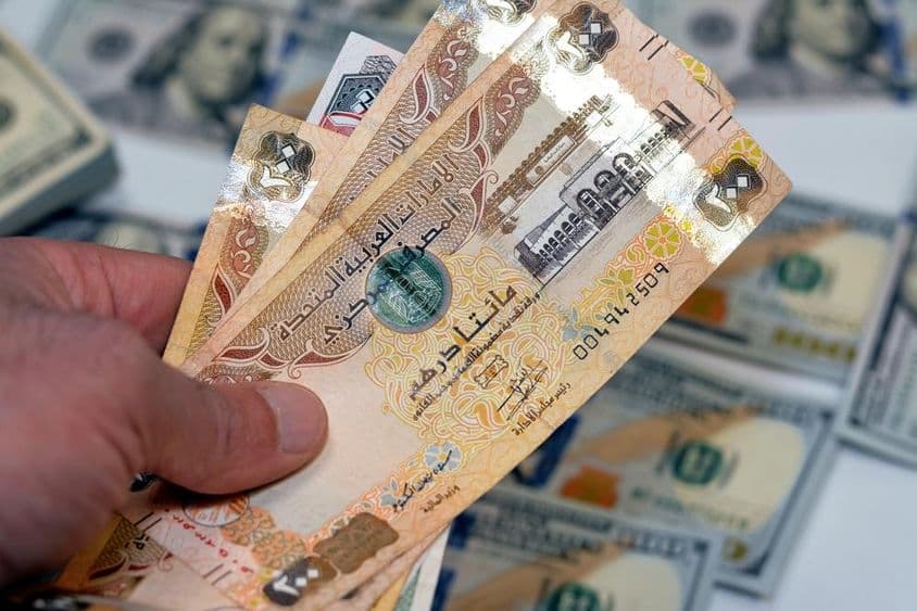 Muž držiaci zväzok bankoviek v hodnote 200 dirhamov Spojených arabských emirátov.