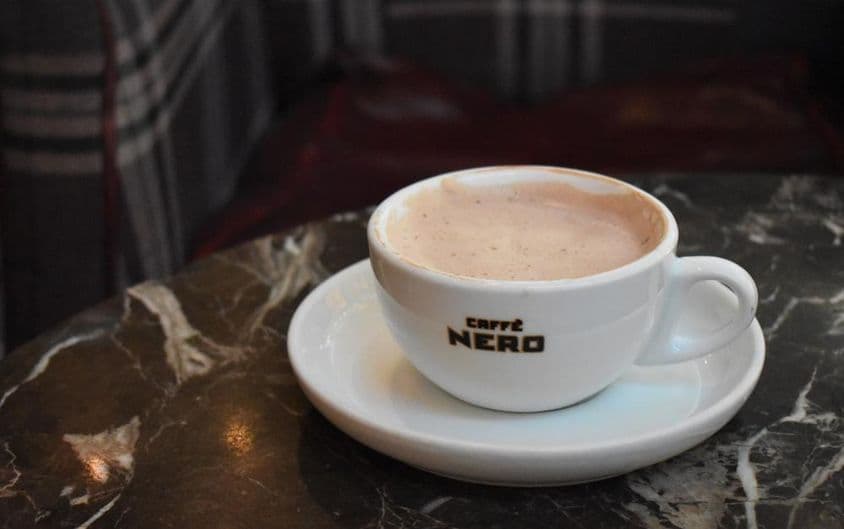 Šálka horúcej čokolády na mramorovom stole v Caffe Nero.