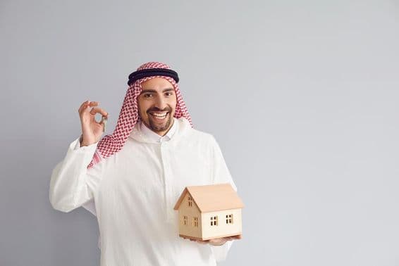Arabský mužský realitný agent držiaci model domu.