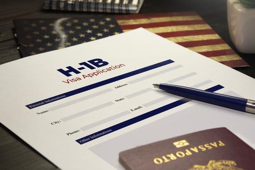 Žiadosť o americké víza H-1B na stole s pasom.