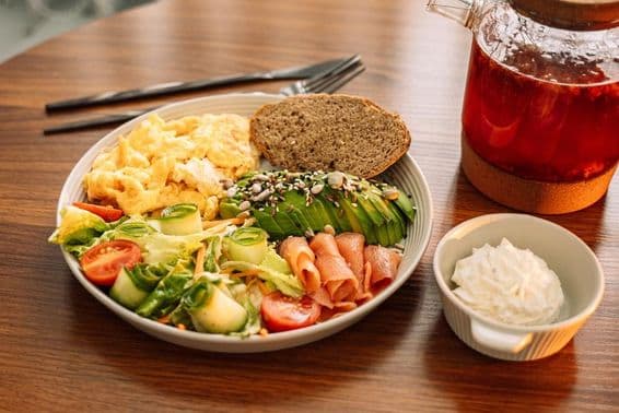 Zdravé raňajky s vajíčkami, avokádom, zeleninou, šalátom a čajom z malín.