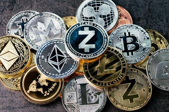 Symboly kryptomien na lesklých strieborných a zlatých fyzických minciach.
