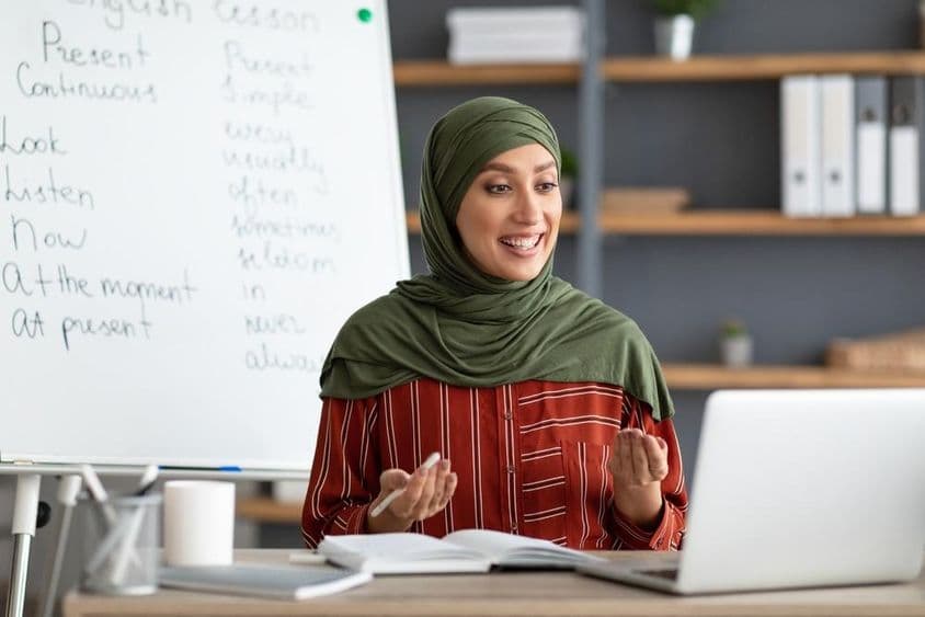 Usmievajúca sa arabská učiteľka v šatke iniciuje videohovor.
