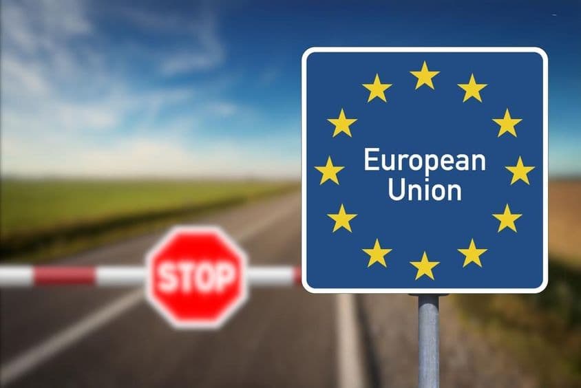 Emblém Európskej únie a hraničný priechod s bariérou a stopkou.