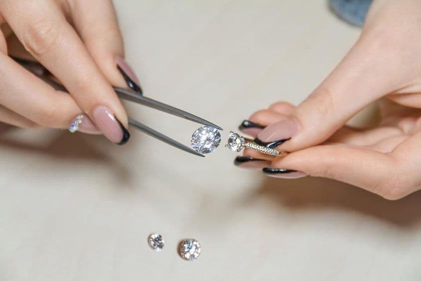 Ruky ženy klenotníka držiace drahokam.