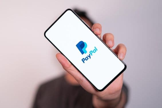 Muž držiaci telefón s viditeľným logom PayPal na obrazovke telefónu.