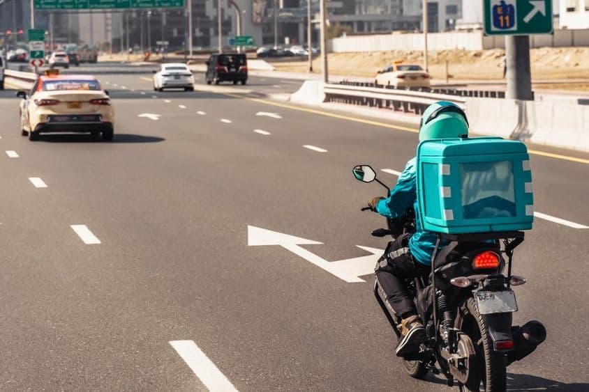 Dubaj, muž na motorke pre online doručovanie jedla.