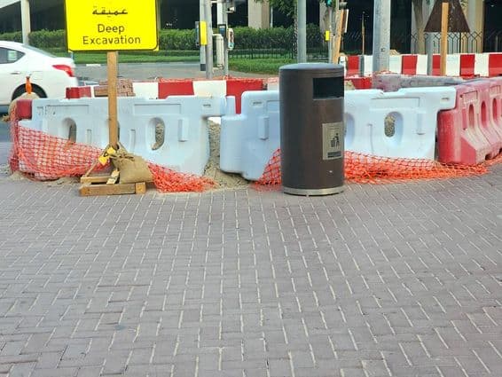 Oprava cesty obklopená plastovými bariérami a oranžovou bezpečnostnou sieťou.