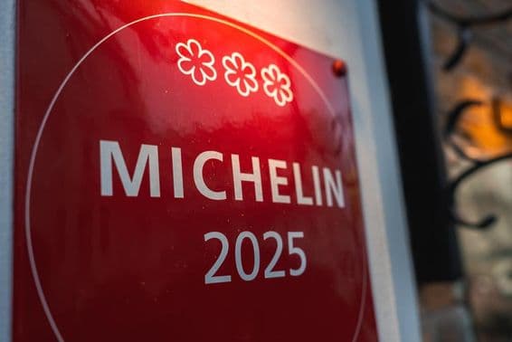 Červená, trojhviezdičková Michelin plaketa 2025 na svetlej stene.