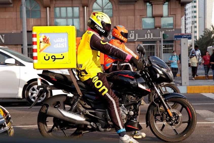 Motocyklový kuriér doručujúci na ulici v Dubaji.