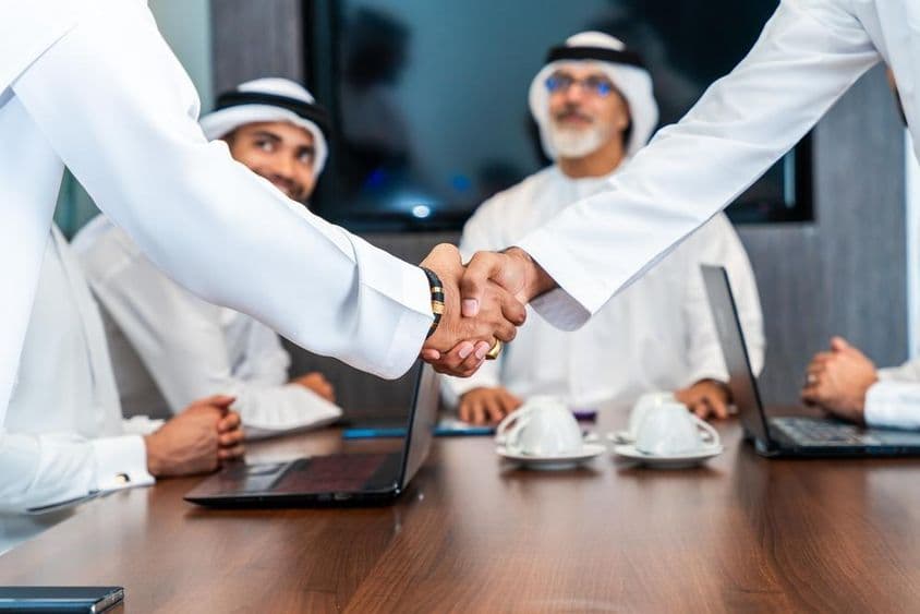 Biznismeni z Blízkeho východu v emirátskej kandure pracujúci v zasadacej miestnosti v Dubaji.