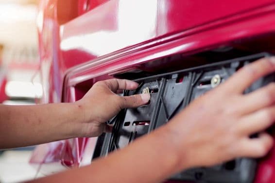 Mechanik vymieňa poznávaciu značku auta v servisnom centre.