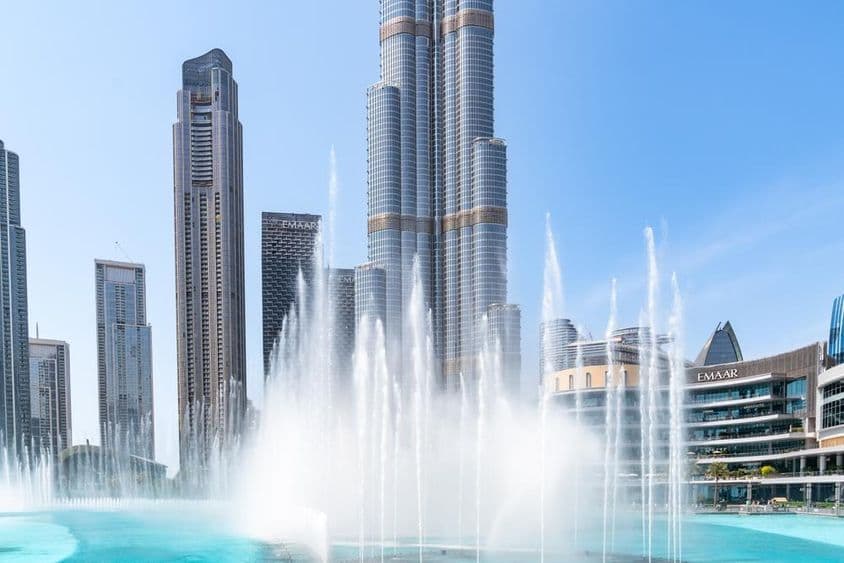 Pohľad na Dubajskú fontánu a vysoký mrakodrap Burj Khalifa počas slnečného dňa v Dubaji.