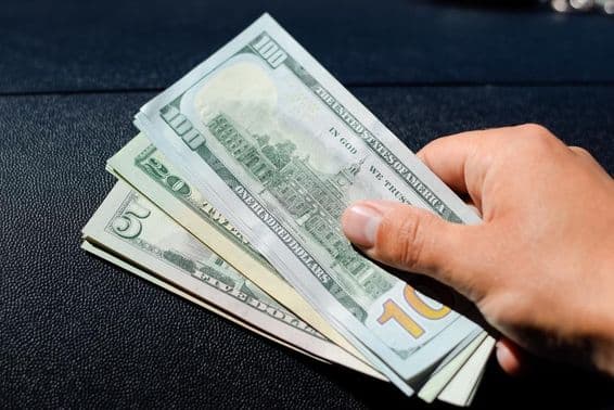 Balík dolárov v ruke muža.