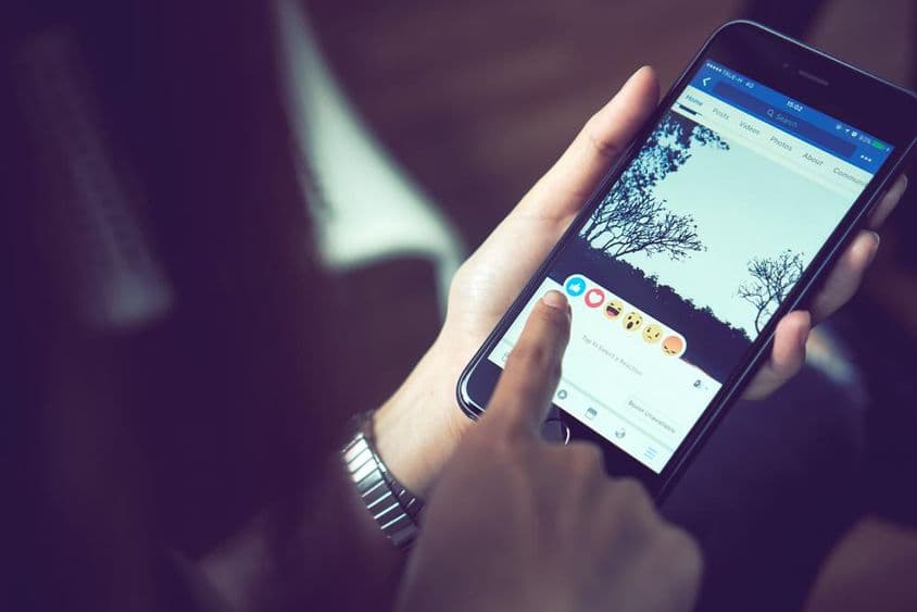 Ruka stláčajúca aplikáciu Facebook na Apple iPhone 6.