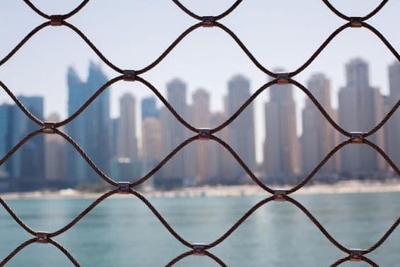 Pohľad na mrakodrapy v Dubaji cez železné mreže.