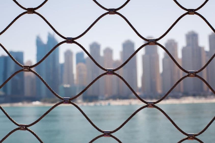 Pohľad na mrakodrapy v Dubaji cez železné mreže.