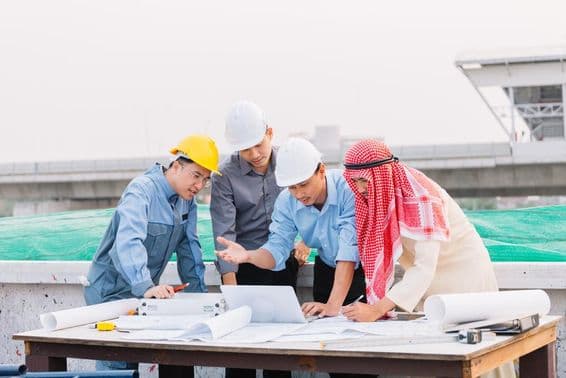 Arabský obchodník, inžinier a pracovník sa venujú stavebným plánom pomocou notebooku.