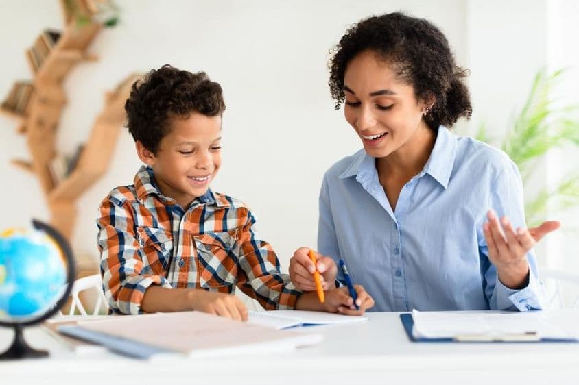 Mladá učiteľka vysvetľujúca lekciu mladému chlapcovi.