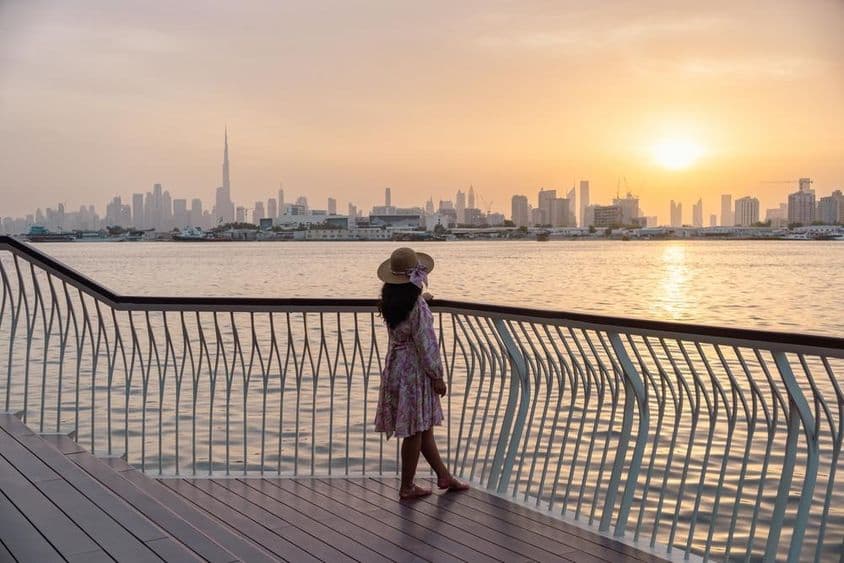 Mladá žena sledujúca panorámu Dubaja pod západom slnka.