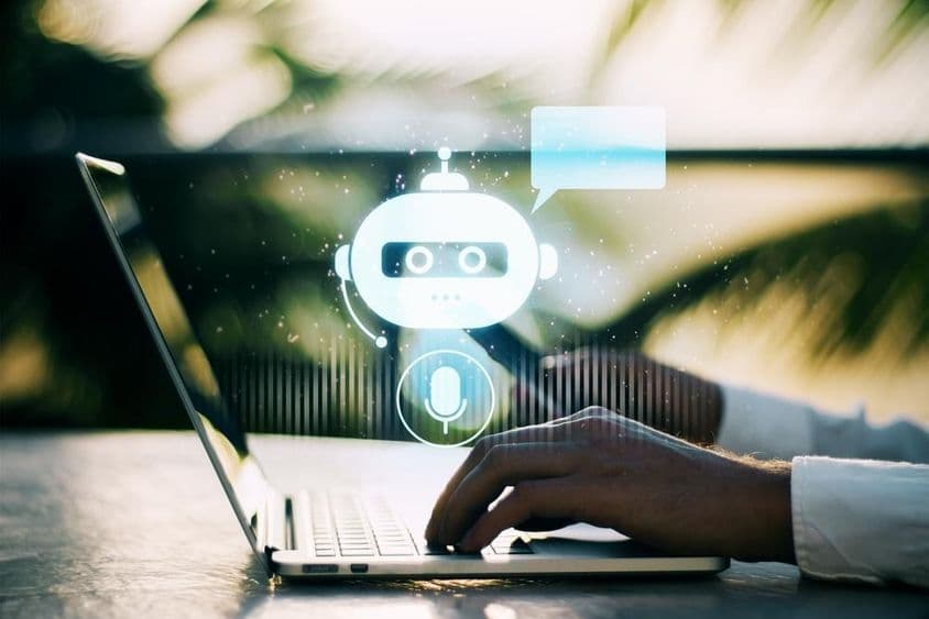 Osoba píšuca na laptop s rozmazaným vonkajším pozadím obsahujúcim ikonu chatbota.