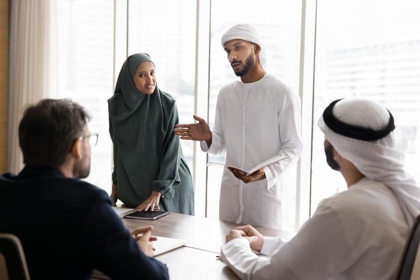Skupina mladých arabských manažérov v tradičnom moslimskom oblečení predstavuje projekt európskym obchodným partnerom.