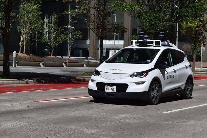 Biele autonómne auto s dozorom jazdiace v finančnom centre mesta.