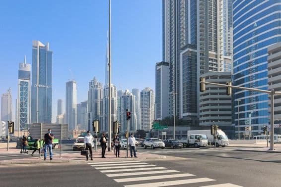 Ľudia kráčajúci na priechode pre chodcov v obchodnej štvrti Dubaja.