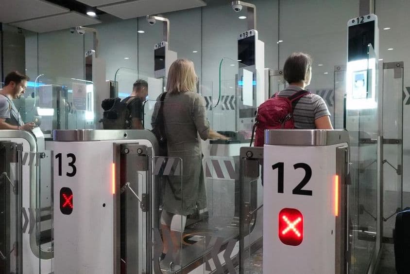 Cestujúci leteckej spoločnosti prechádzajúci automatickými kontrolnými bodmi pre pasy.