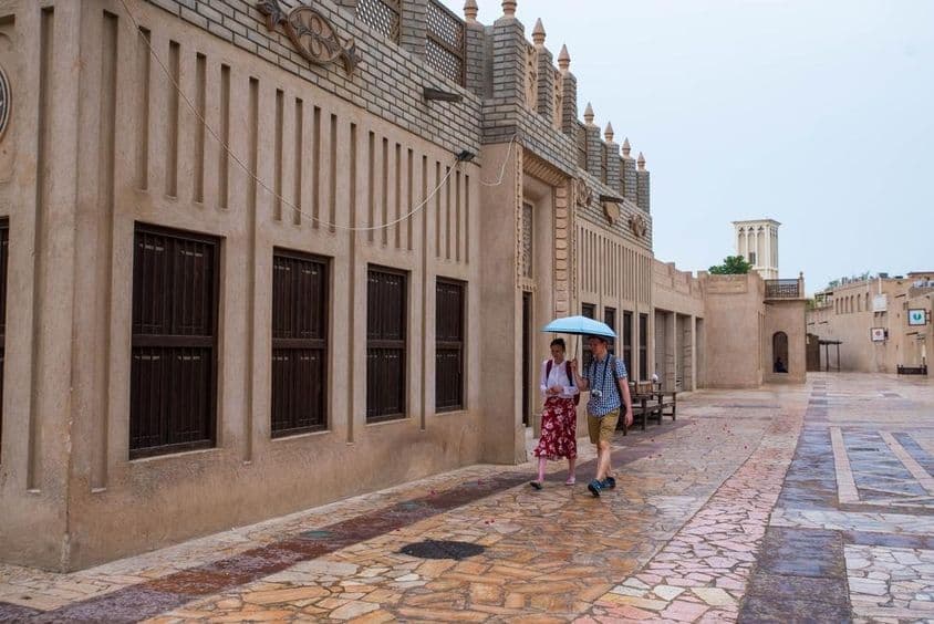 Turistický pár, ktorý kráča pod dáždnikom po uliciach Dubaja.