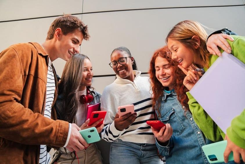 Študenti používajúci mobilné telefóny počas prestávky.