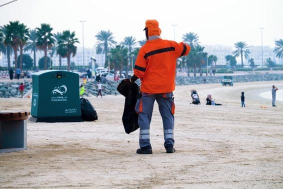 Dubaj, Spojené arabské emiráty, pracovník čistí pláž.
