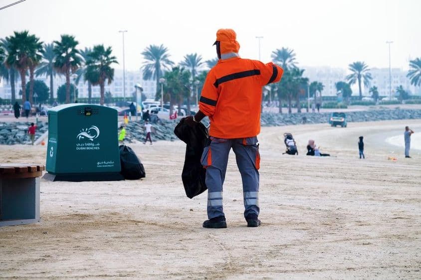 Dubaj, Spojené arabské emiráty, pracovník čistí pláž.