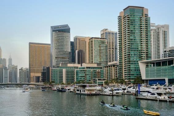 Večerný pohľad na kanál, prístav s loďami, dubajskú promenádu a mrakodrapy.
