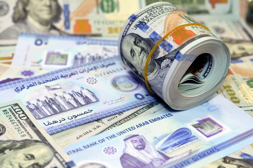 100 dolárové americké bankovky a dirhamy.