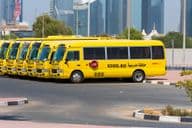 Rada žltých dubajských školských autobusov zaparkovaných vonku.