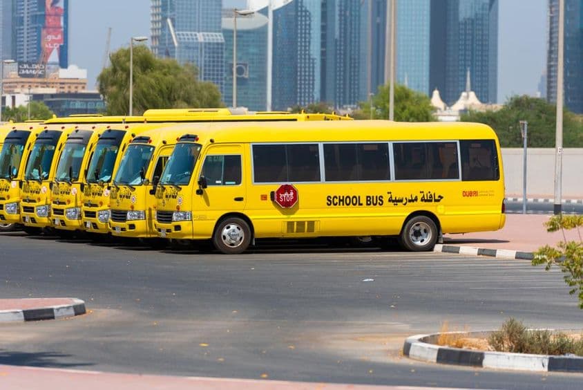 Rada žltých dubajských školských autobusov zaparkovaných vonku.