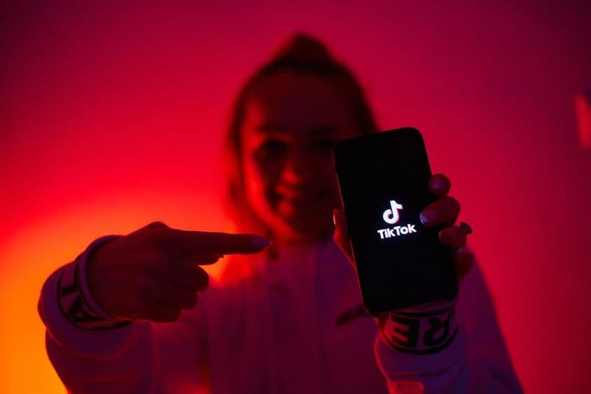 Dievča s tmavou stranou, drží smartfón, propaguje sociálne médiá.