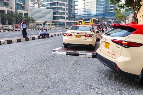 Skupina taxikárov čakajúcich na pasažierov pred hotelom v Dubaji.