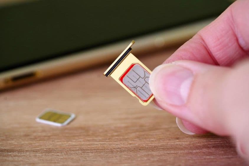 Osoba vkladajúca SIM kartu do zadnej strany mobilného telefónu.