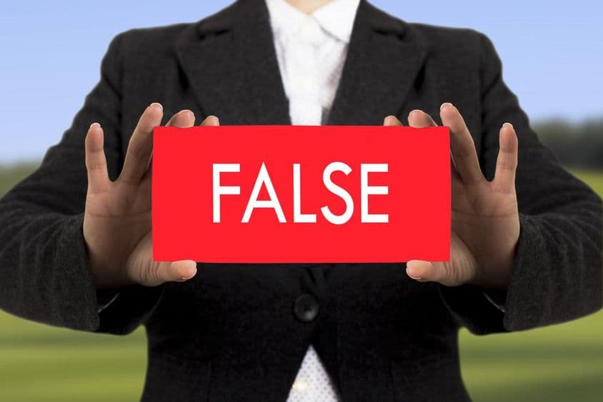 Podnikateľka v čiernom saku drží kartu s textom fake.