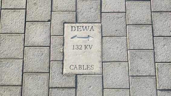 Značka varujúca pred káblami na podlahe z kamenných dlaždíc v Dubaji.