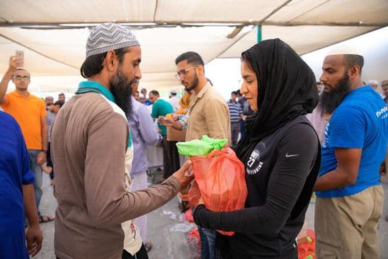 Dobrovoľníci rozdávajú potravinové balíky pracovníkom počas Iftar jedla.
